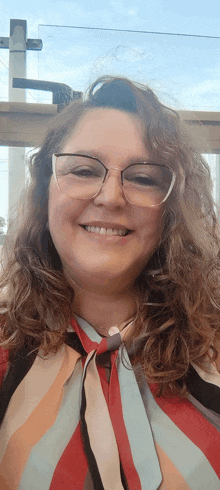 a woman wearing glasses and a striped shirt smiles at the camera