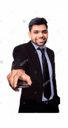 a man in a suit and tie is smiling and pointing at the camera