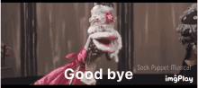 a sock puppet in a pink dress says good bye