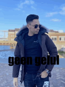 a man wearing sunglasses and a jacket stands in front of a sign that says geen geul