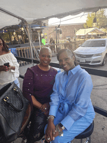 two women are posing for a picture with a car in the background that has a license plate that starts with the letter c