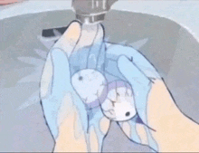 a person is washing their hands in a sink while holding a small object .