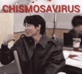 a man sitting in front of a sign that says chismosavirus