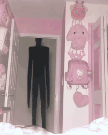 a shadow of a person standing in a doorway with pink hello kitty backpacks hanging on the wall