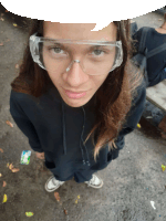 a girl wearing glasses and a black hoodie looks at the camera