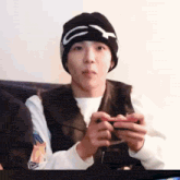 a young man wearing a black beanie is holding a video game controller .