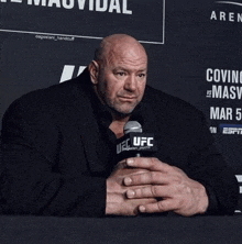 a man in a suit holds a microphone that says ufc on it