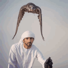 a man is holding a bird that is flying in the air above him