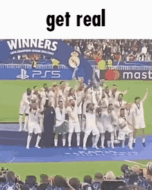 a group of soccer players are standing on a stage holding a trophy and a sign that says get real .