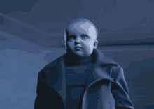 a little boy in a black coat and turtleneck looks at the camera