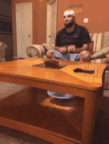 a man with a bandage on his head sits on a couch next to a coffee table with a cake on it