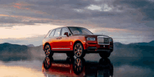 a red rolls royce car is parked in the water