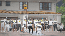 a group of people standing in front of a house with one wearing a shirt that says ' assault rifle '