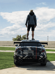 a man standing on top of a car with a california license plate that says wbaxt15