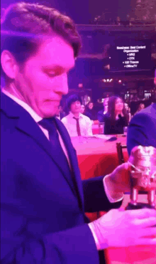 a man in a suit and tie holds a trophy in front of a screen that says newsweek best content