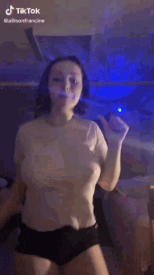 a woman in a white t-shirt and black shorts is dancing in a room .