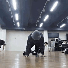 a man wearing a hat is doing push ups on the floor in a dance studio .