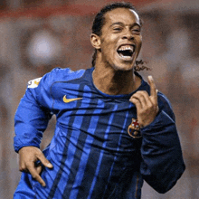 a soccer player wearing a blue nike jersey is laughing and giving the middle finger