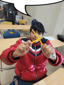 a boy in a red jacket is holding two pencils in his hands