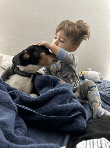 a little boy laying on a bed with his dog