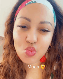 a woman wearing a headband is making a funny face with the word muah on the bottom right