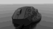 a black computer mouse with a pattern of circles on it sits on a black surface