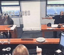 a man is giving a thumbs up while sitting at a desk in front of a screen that says 2024-3820 on it
