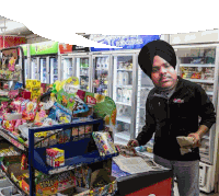 a man in a turban is standing in front of a pepsi fridge