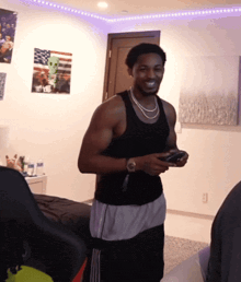 a man in a black tank top is smiling while holding a game controller
