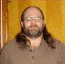 a man with long hair and a beard is wearing glasses and a brown shirt .