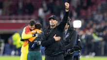 a man holds his fist up in the air while standing on a soccer field