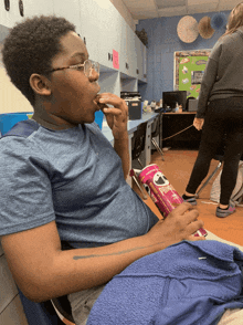 a boy is sitting in a chair eating pringles chips