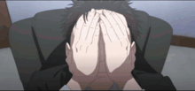 a man is covering his face with his hands in a chair