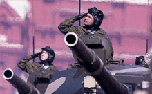 a group of soldiers are standing on top of a tank saluting .