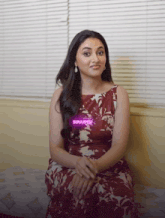 a woman in a floral dress is sitting on a couch with a sticker that says suuuper on it