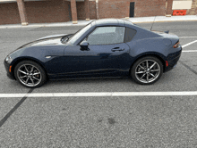 a black sports car is parked in a parking lot next to a brick building