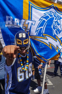 a man wearing a mask with the number 55 on it holds a flag