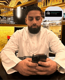 a man sitting at a table looking at his phone with a speech bubble that says i 'm not ready on it