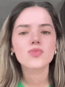 a close up of a woman 's face with a green shirt on