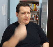 a man in a black shirt is making a funny face in front of a shelf with books on it