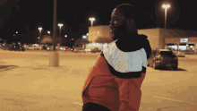 a man in a red white and black jacket stands in a parking lot in front of a target store