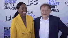 a man and a woman are posing for a picture in front of a wall that says endent spirit awards on it