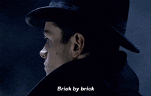 a close up of a man 's face with the words brick by brick below him