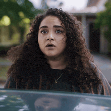 a woman with curly hair is sitting in a car