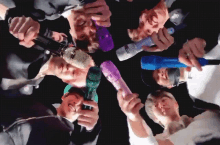 a group of people are holding microphones together in a circle