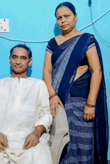 a man in a white shirt sits next to a woman in a blue striped dress