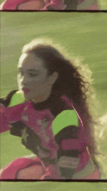 a woman in a pink and yellow outfit is standing on a field