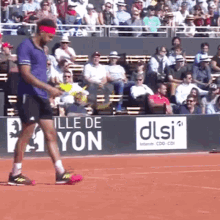 a man in a purple shirt stands on a tennis court in front of a sign that says ille de yon