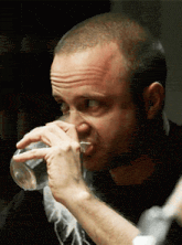 a man is drinking a glass of water from a clear bottle