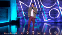 a man stands on a stage with a microphone in front of a nbc logo
